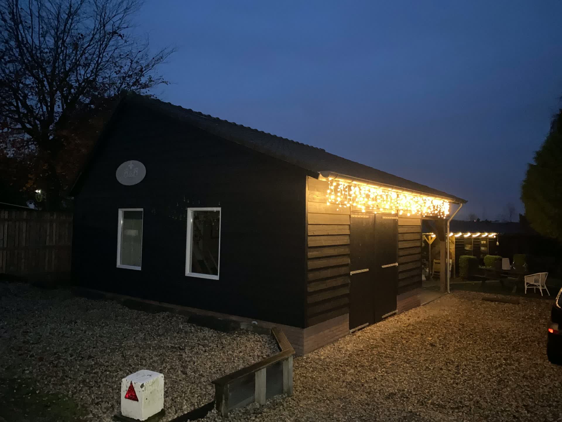 Buitenkant van het huisje voor 9 personen met lichtjes in de avond