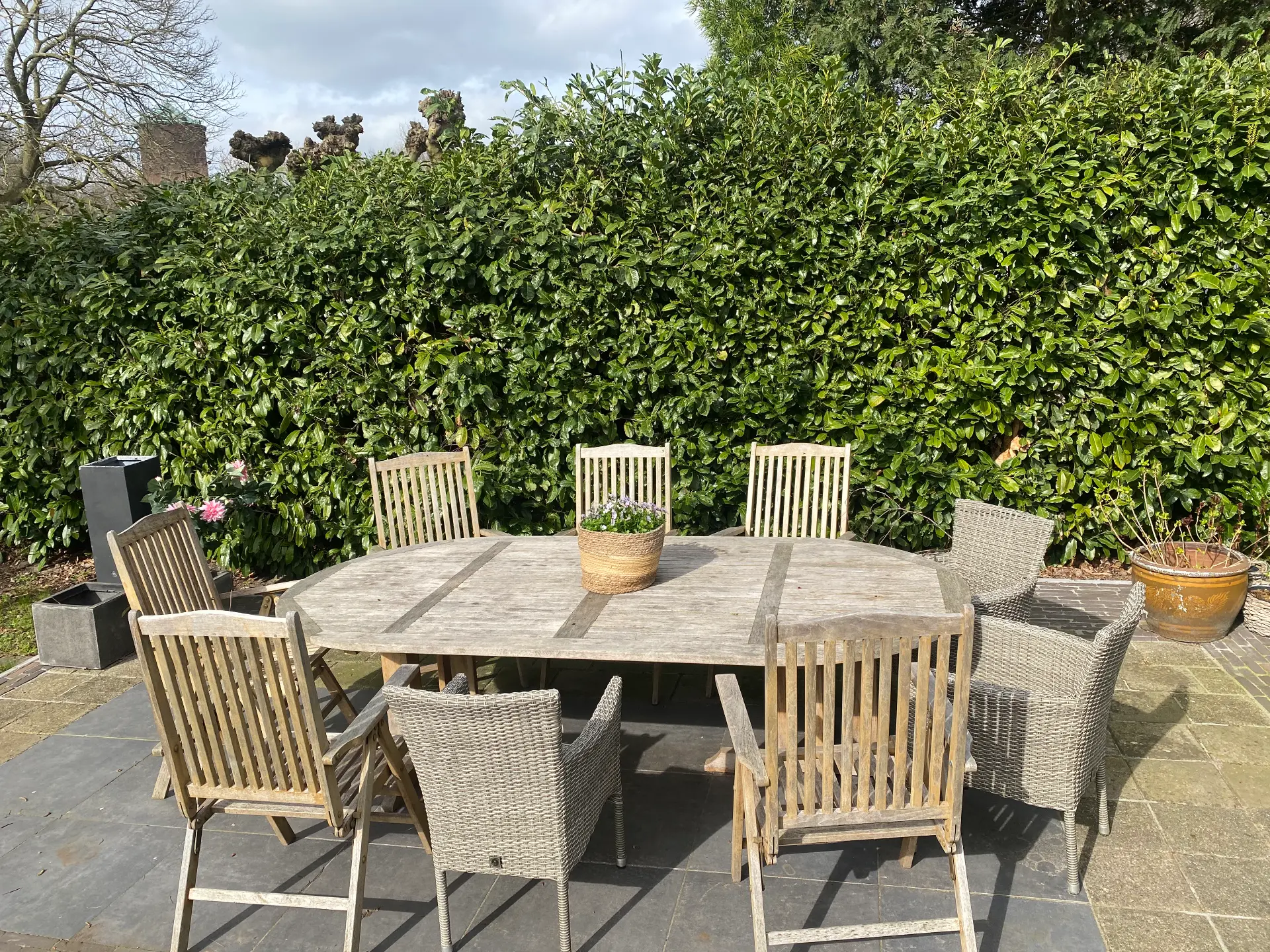 Grote houten tuintafel met stoelen bij het huisje voor 9 personen