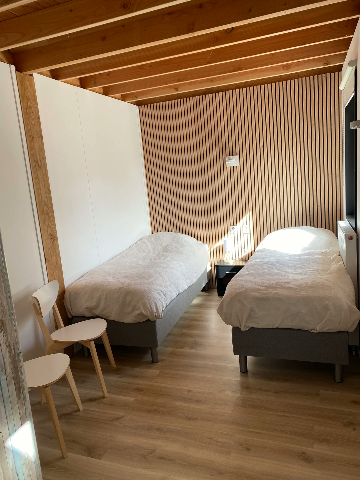 Huisje voor 11 personen: slaapkamer met twee eenpersoonsbedden en houten plankenwand