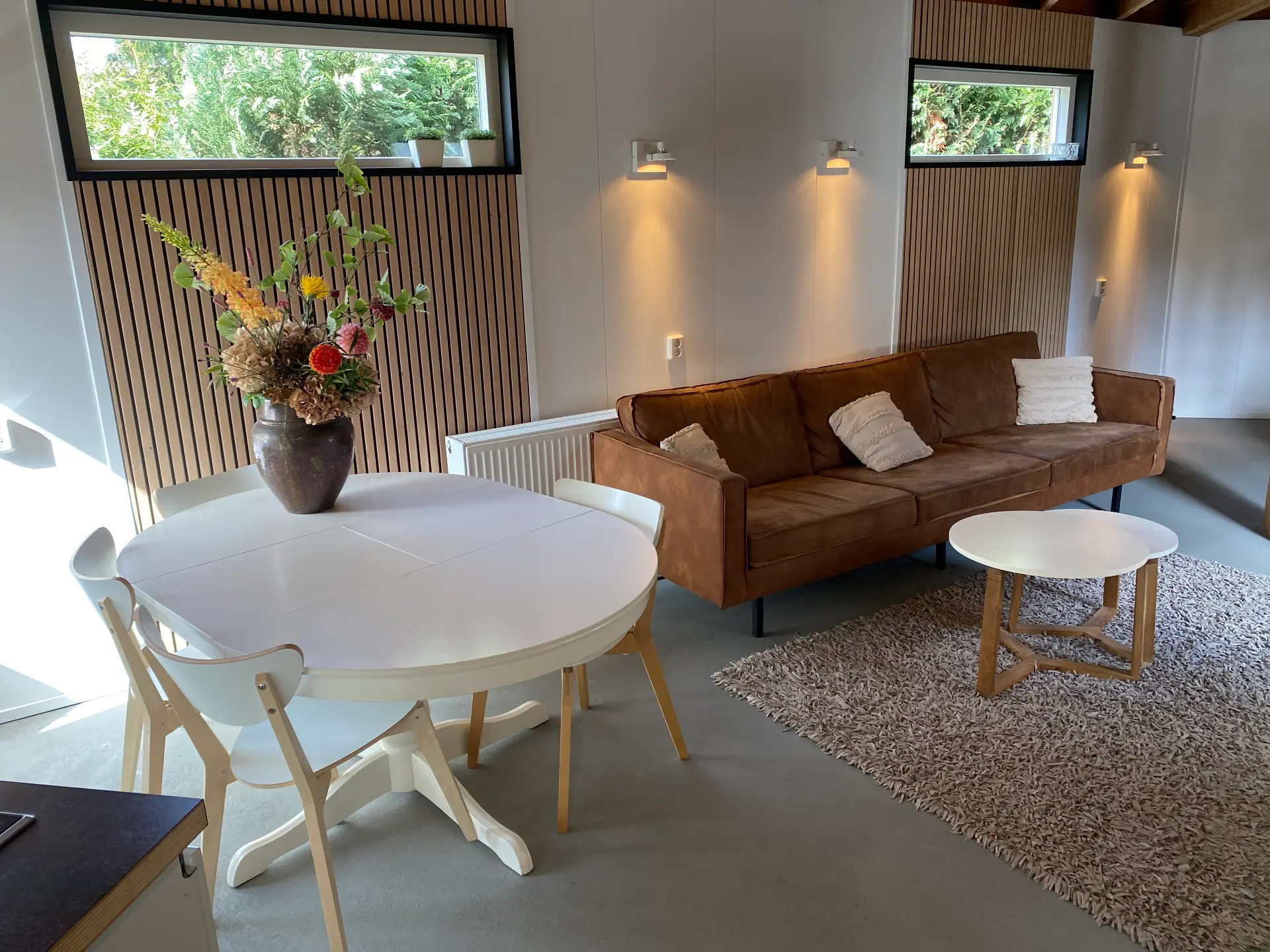 Huisje voor 11 personen: woonkamer met ronde eettafel en bruine bank