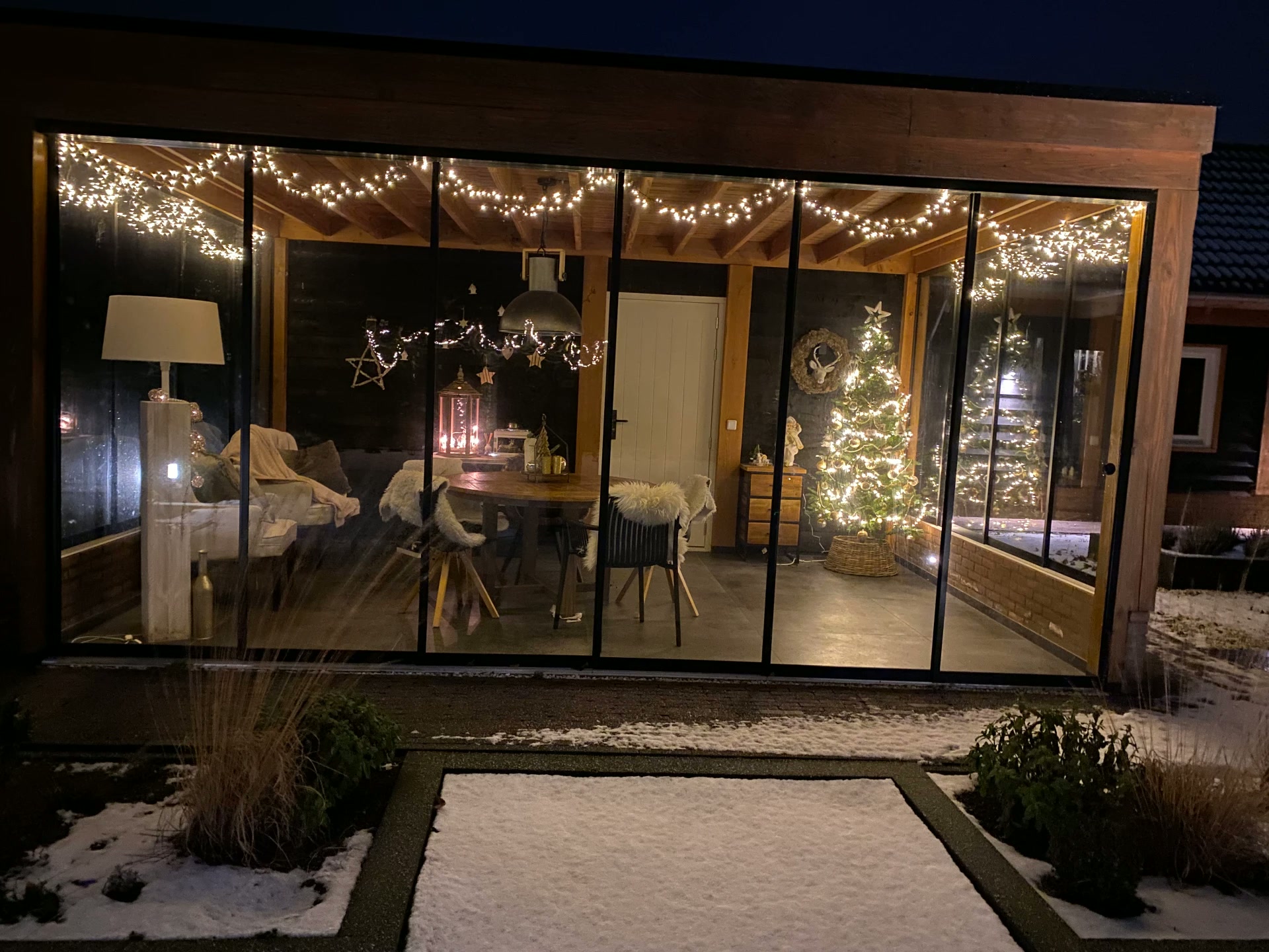 Het glazen paviljoen met kerstverlichting in de sneeuw