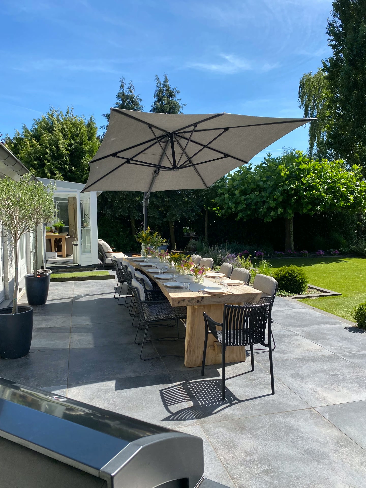 Lange buitentafel met parasol op het terras