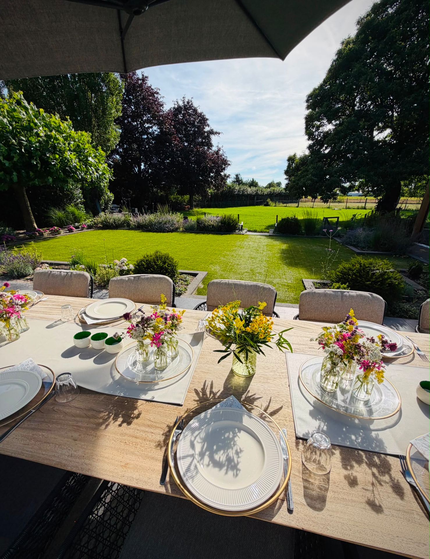 Gedekte tuintafel met bloemen onder de parasol